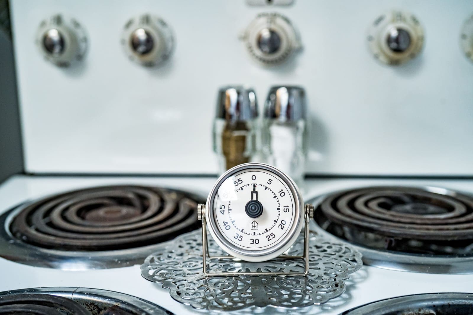 An analog kitchen timer on a gas stove