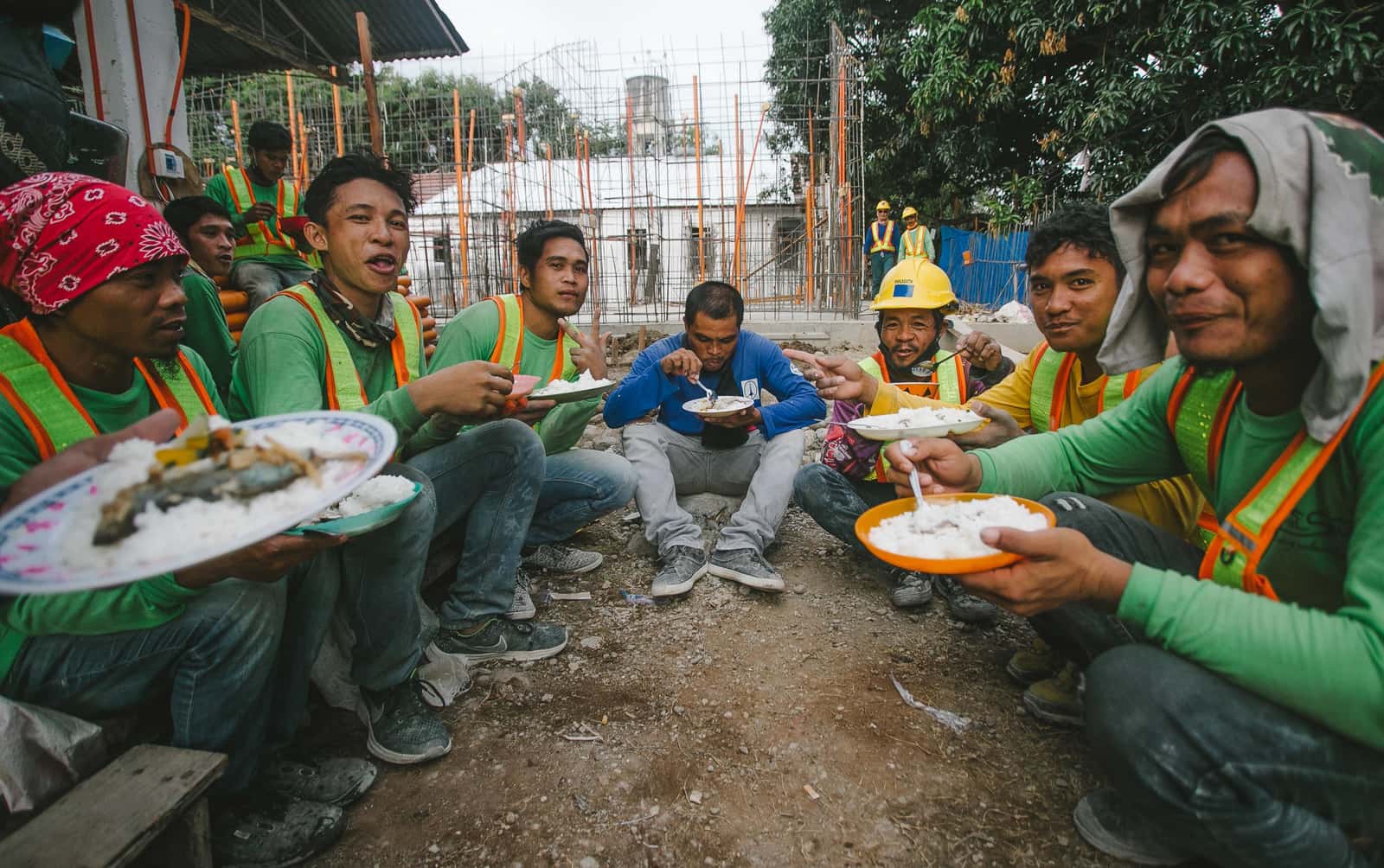 Construction workers eating lunch together at an outdoor site