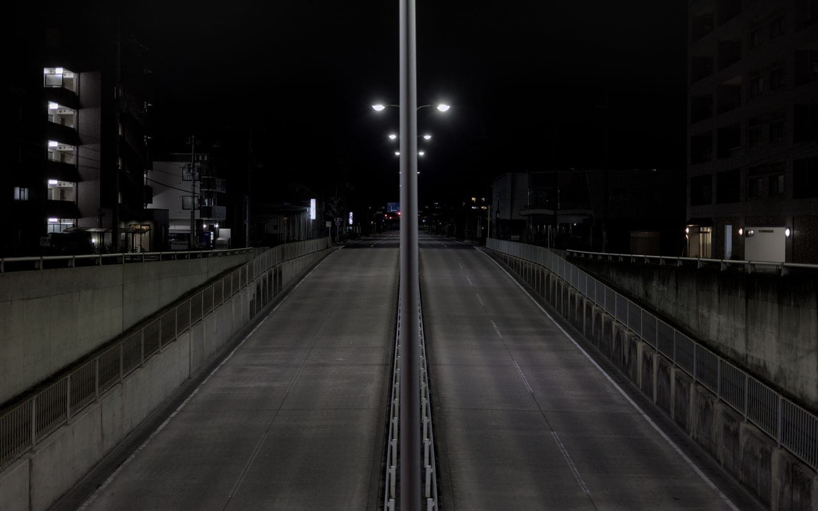 An empty city highway at night lined with streetlights