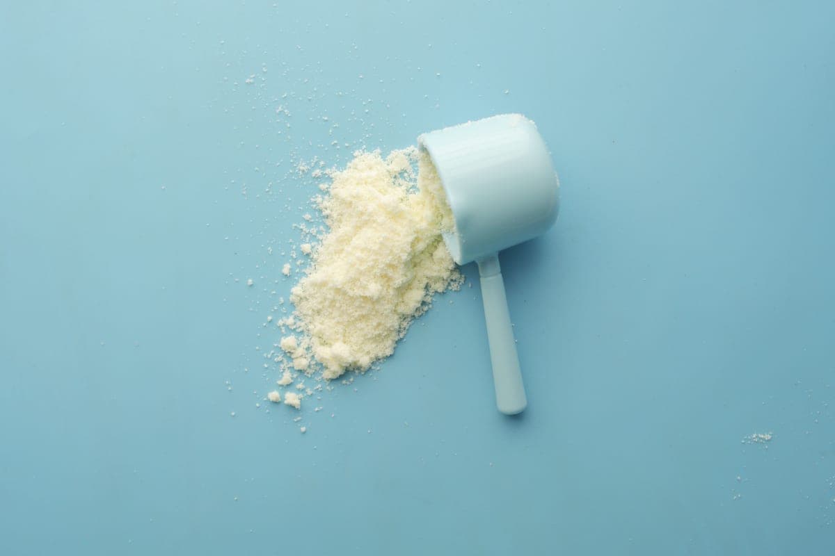 Protein powder spilled from a scoop on a blue background