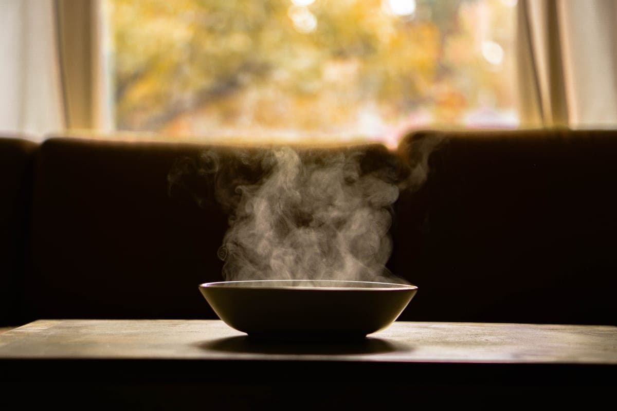 A steaming bowl of soup on a wooden table