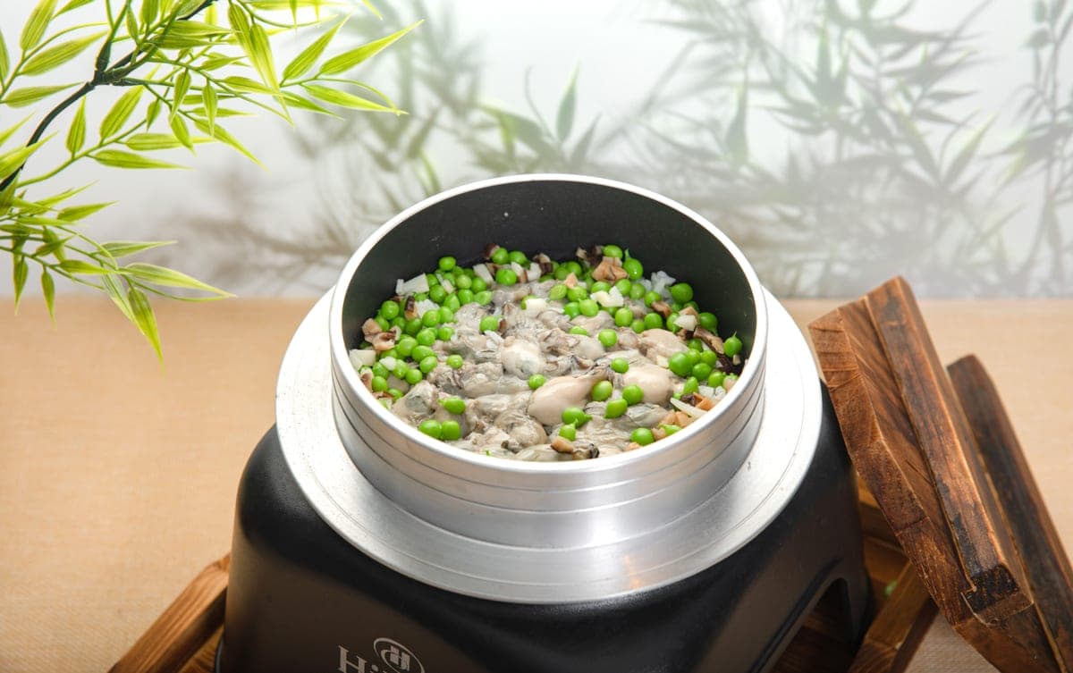 Steamed rice with oysters and green peas in a rice cooker