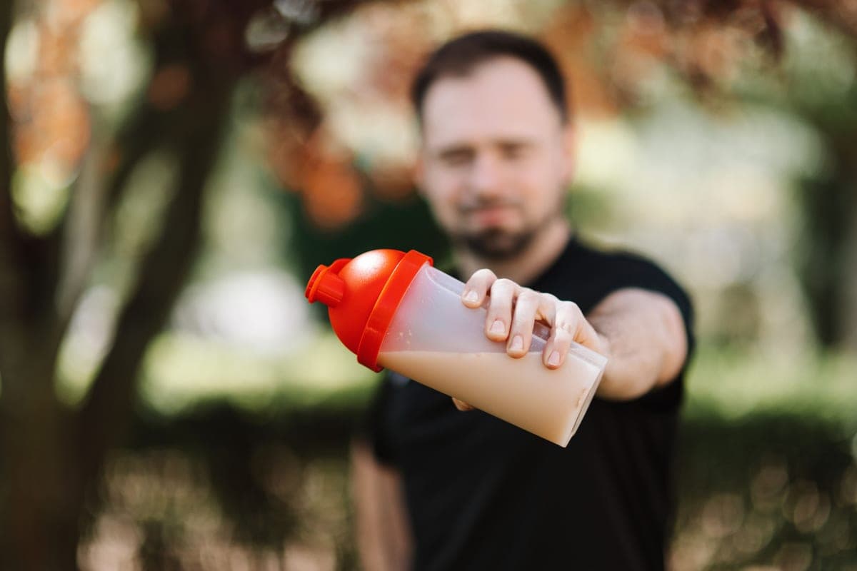 A man holding a plastic shaker bottle outdoors